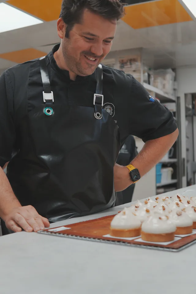 Pâtissier dans son laboratoire devant une plaque de pâtisseries.